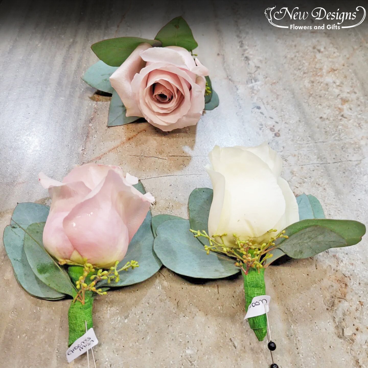 3 Boutonniere's, 2 with a dusty pink coloured Rose, and the Groom's with a white Rose, with eucalyptus greenery